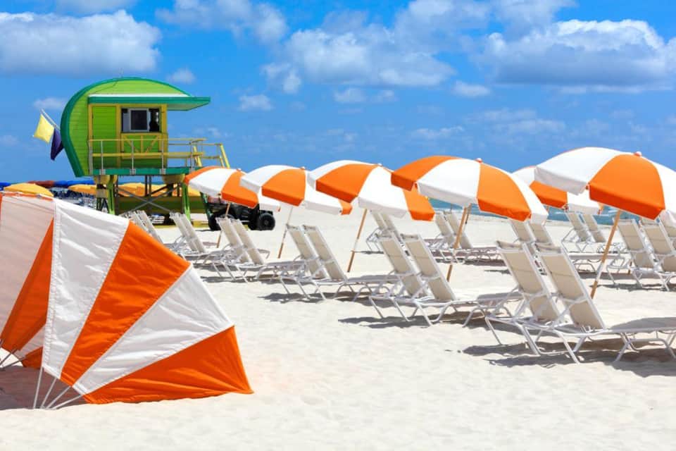 Miami beach with lifeguard stand and rows of orange and white umbrellas