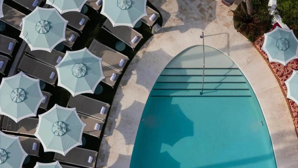 Aerial view of turquoise resort pool with sunshade umbrellas and lounge chairs