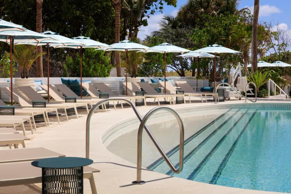 Contemporary pool with lane markers, loungers, and canopy umbrellas