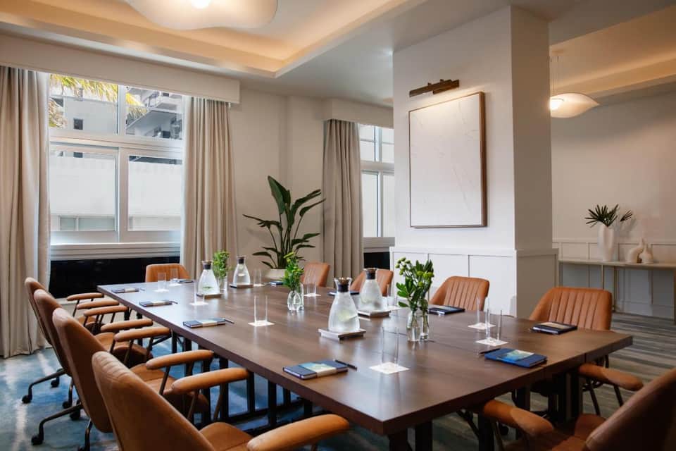 Boardroom with long conference table, leather chairs, and tropical window views