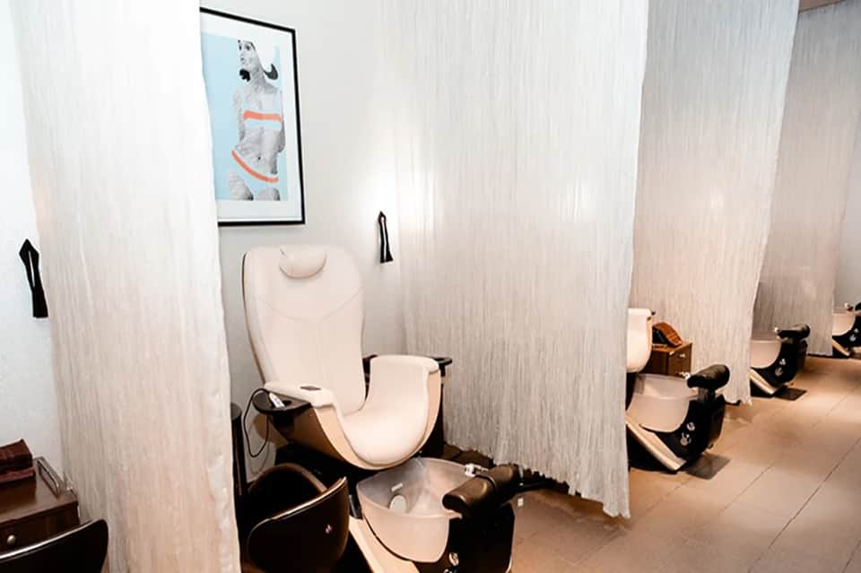 Modern spa pedicure station with white chair and private curtained booth