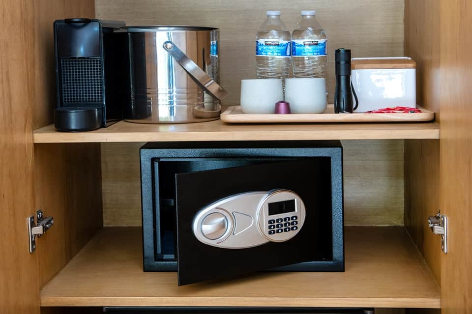 In-room safe in wooden cabinet with coffee maker and bottled water amenities