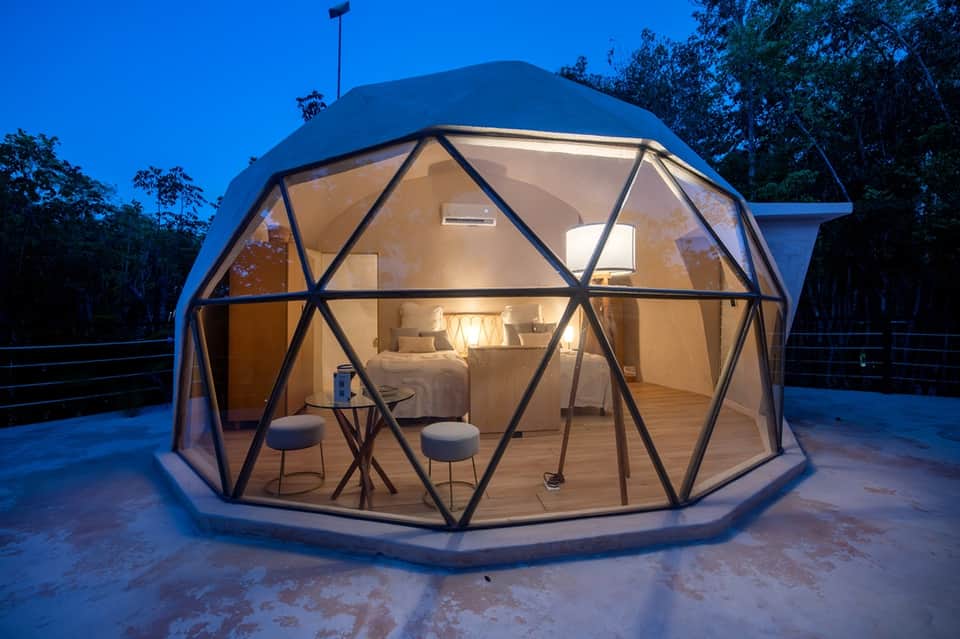 Illuminated geodesic dome glamping structure with interior bedroom at night