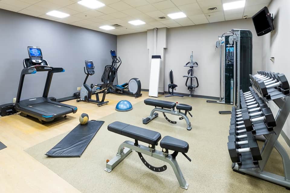 Well-equipped fitness center with treadmills, exercise bikes, dumbbells, and strength training equipment