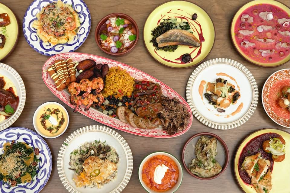 Overhead view of colorful platters with international cuisine including seafood, meats, and prepared dishes