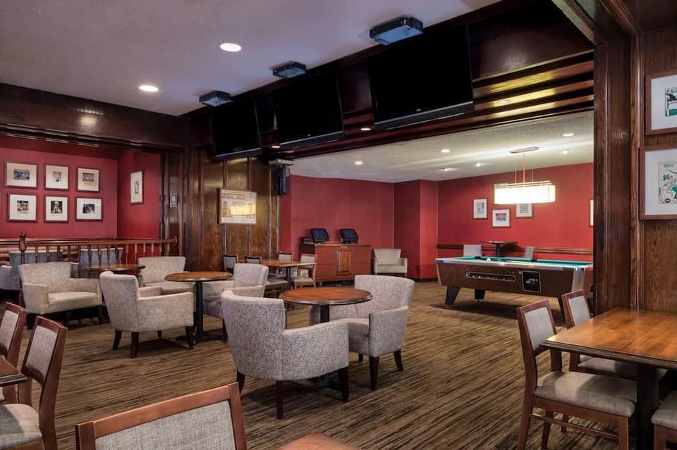 Recreation room with billiards table, red walls, comfortable seating, and mounted televisions
