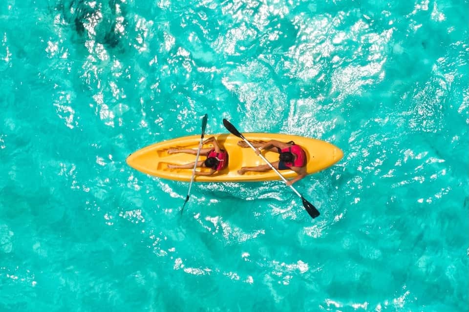 Overhead view of yellow kayak with two people on turquoise tropical water
