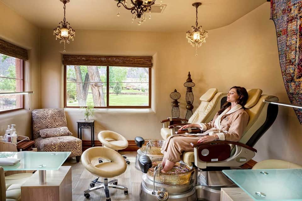 Luxury spa room with pedicure stations, crystal chandeliers, and manicured seating area