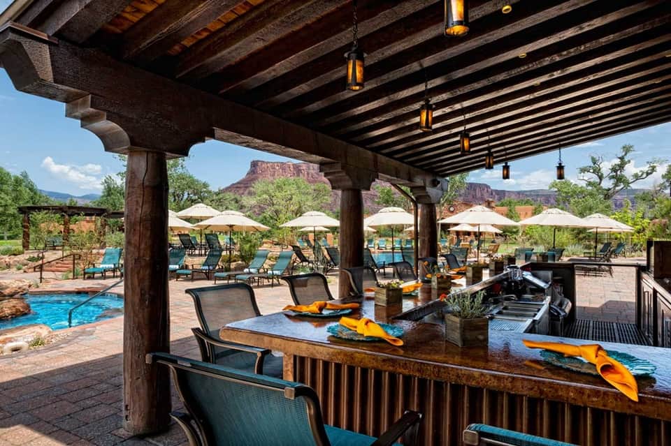 Resort patio with pergola, outdoor bar, lounge chairs, and scenic canyon views with umbrella seating