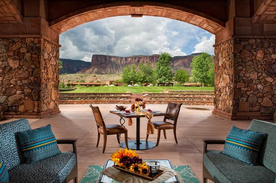 Stone archway framing scenic mountain valley view with patio seating and furniture