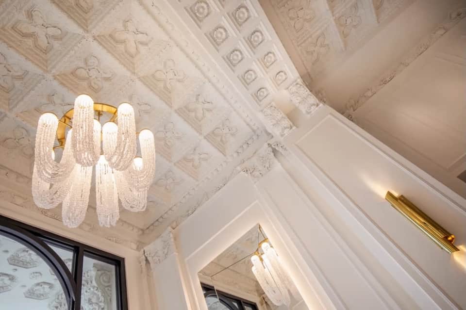 Elegant ornate ceiling with decorative molding and modern crystal chandelier lighting