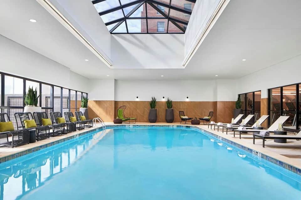 Indoor pool with skylights, wooden accents, lounging chairs with yellow cushions
