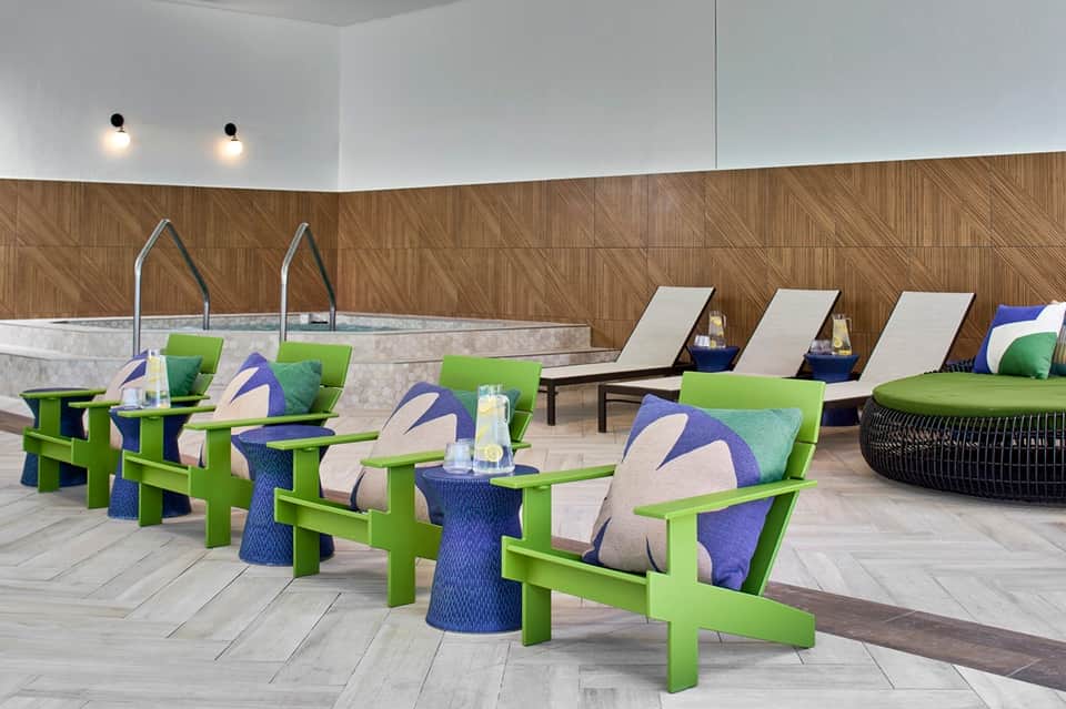 Contemporary spa area with lime-green Adirondack chairs, cushions, indoor pool, and lounge chairs