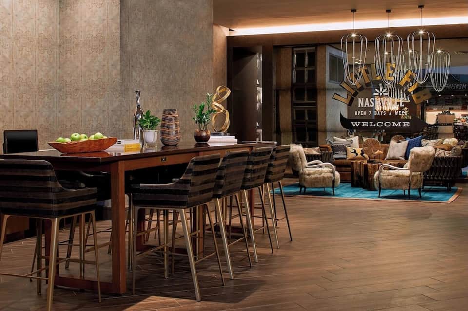 Modern hotel lobby with wood accents, bar counter, high ceilings, and lounge seating area