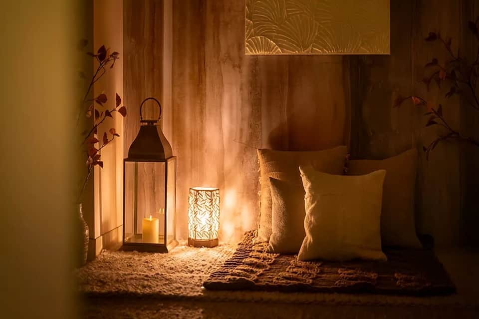 Decorated patio corner with lanterns, candles, throw pillows, and ambient lighting