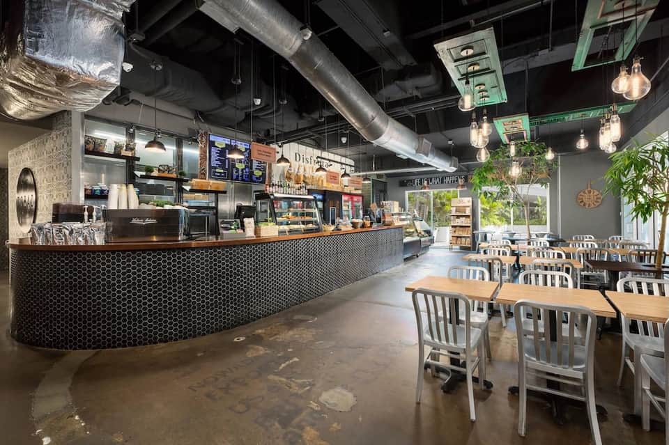 Modern cafe counter with hexagonal tile backdrop, pendant lighting, and dining area