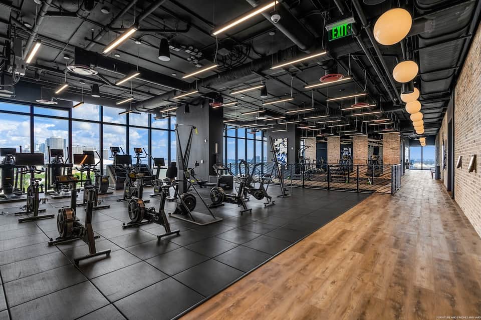Modern high-rise fitness center with spinning bikes, floor-to-ceiling windows, and city views