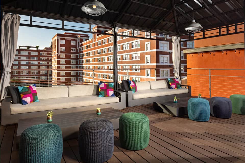 Rooftop lounge with modern seating, colorful pillows, and urban cityscape views