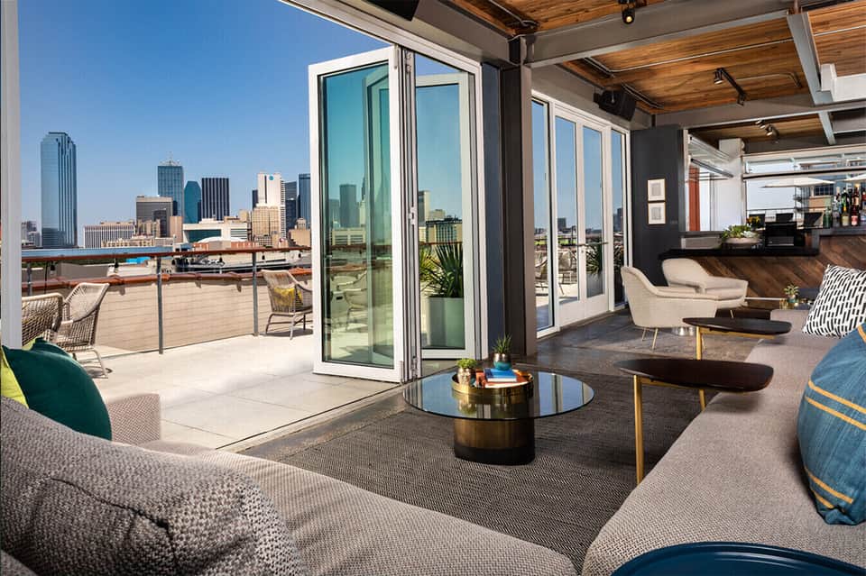 Modern rooftop lounge with floor-to-ceiling windows overlooking city skyline and contemporary furniture