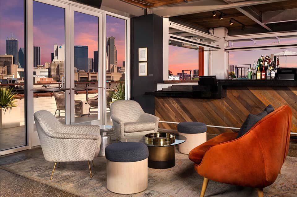Rooftop lounge with city skyline views, modern seating, and full bar at sunset