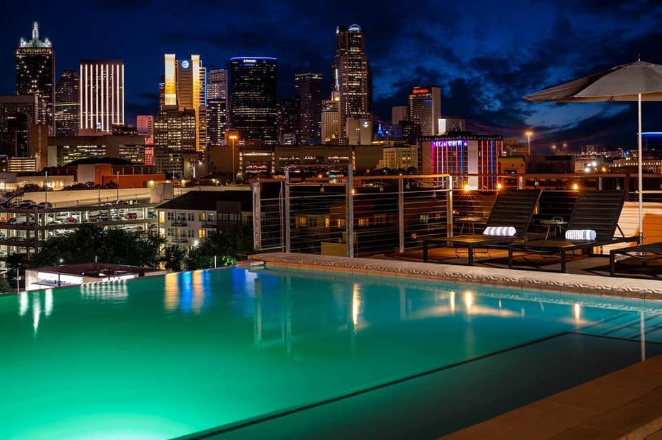 Illuminated rooftop pool with city skyline at night and modern lounge seating