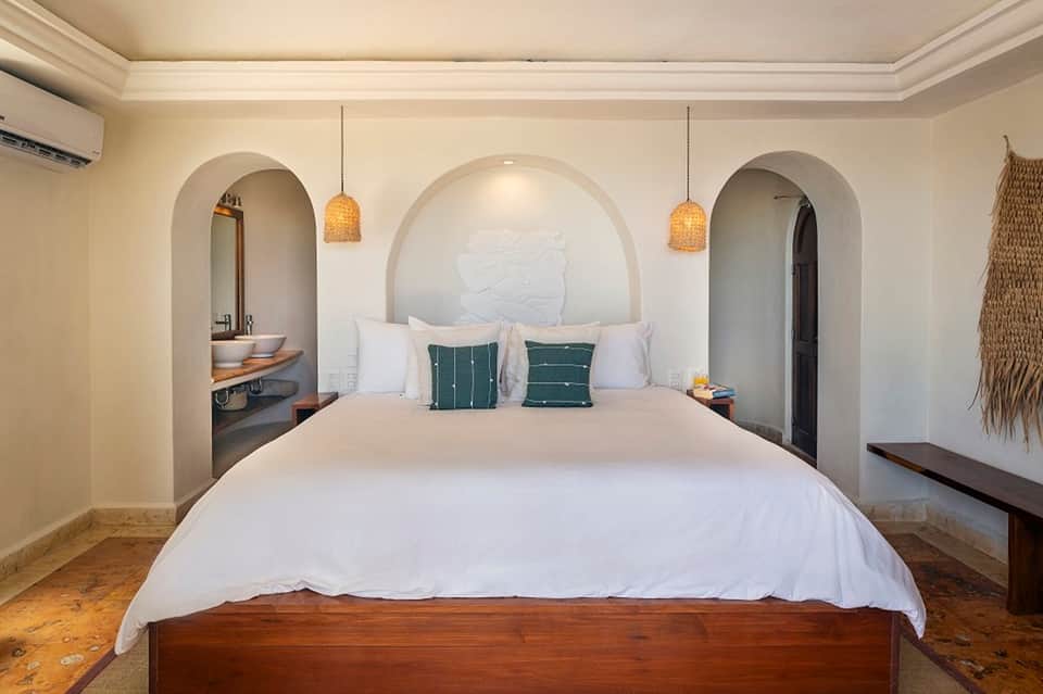Mediterranean-style bedroom with arched alcove headboard and pendant lighting