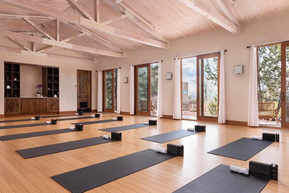 Spacious yoga studio with wooden beams, glass doors, and yoga mats