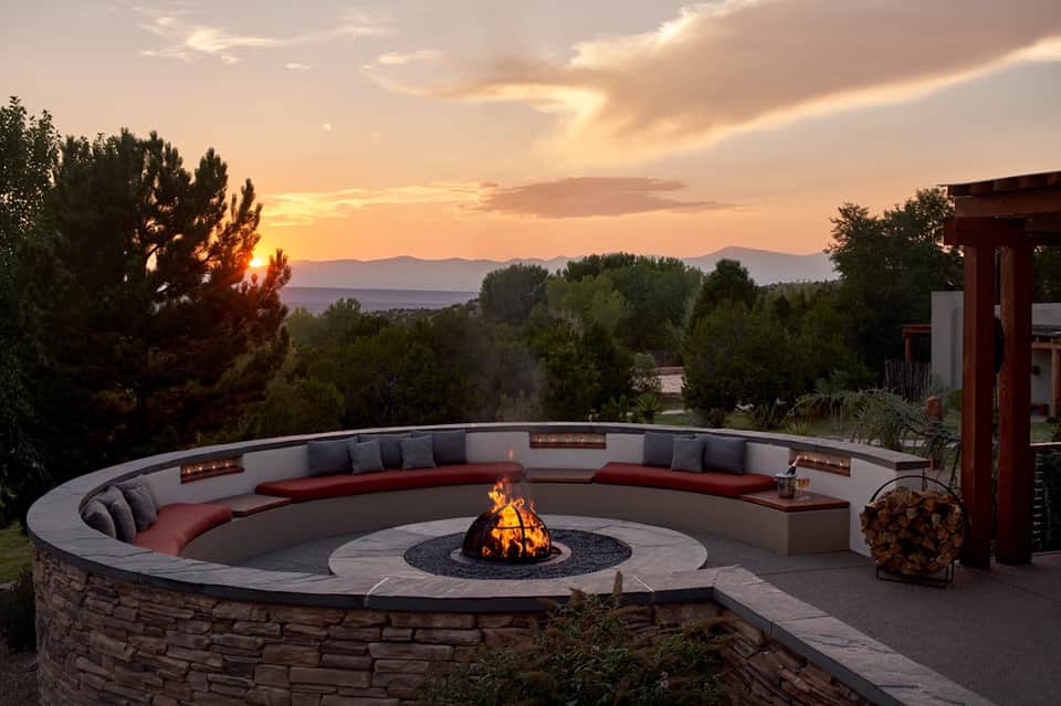 Circular fire pit seating area with built-in bench, mountain sunset views, and evening lighting