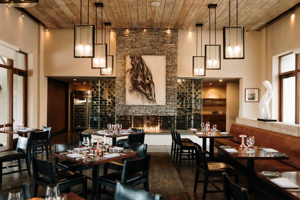 Fine dining restaurant with fireplace, wooden ceiling, and elegant table settings