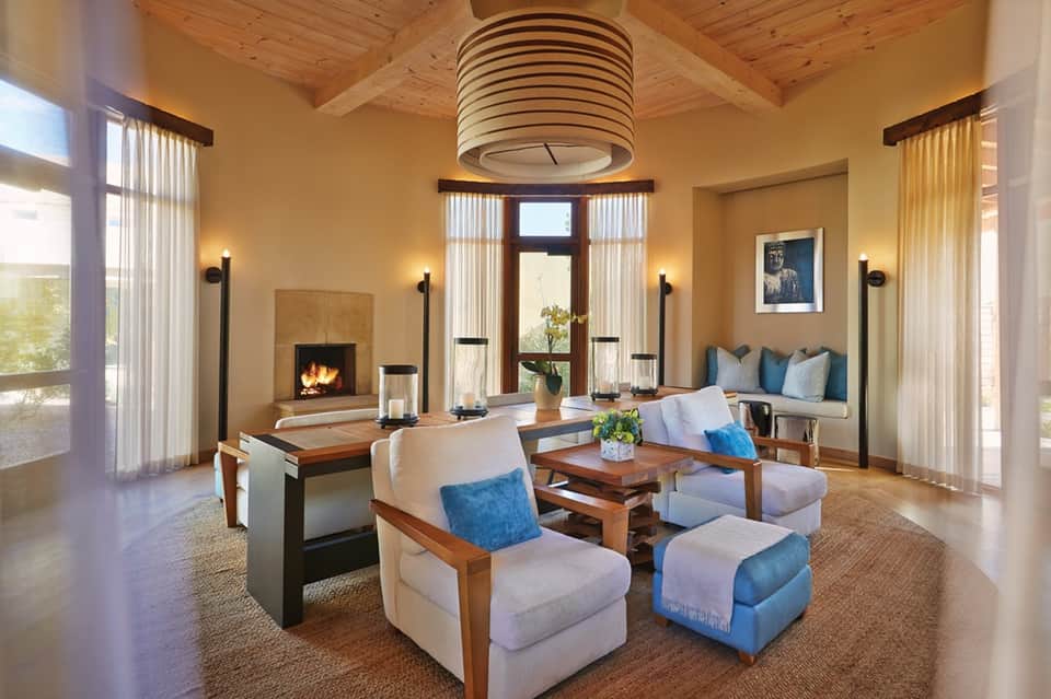 Elegant resort lounge with fireplace, wooden ceiling, modern furniture, and natural light