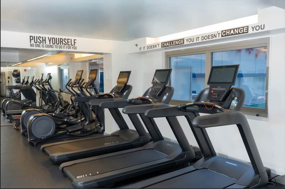 Modern gym with treadmills, elliptical machines, and motivational wall signage