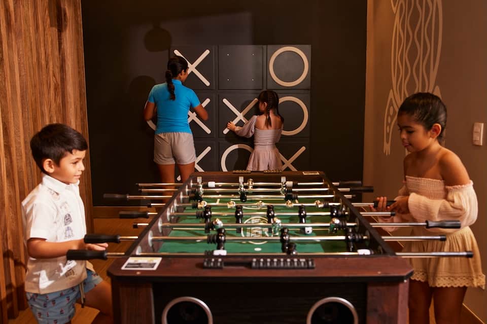 Recreation room with foosball table and large tic-tac-toe wall game, children playing