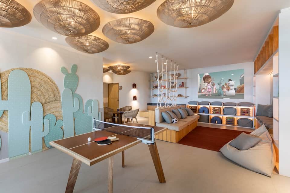Modern game room with ping pong table, lounge seating, and decorative ceiling fixtures
