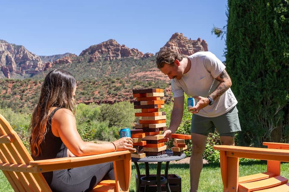 Couple playing wooden block game on patio with red rock mountains in background