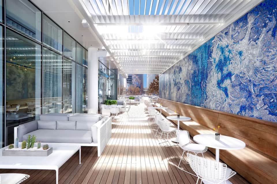 Modern covered terrace with blue mosaic wall, white ceiling, and contemporary seating