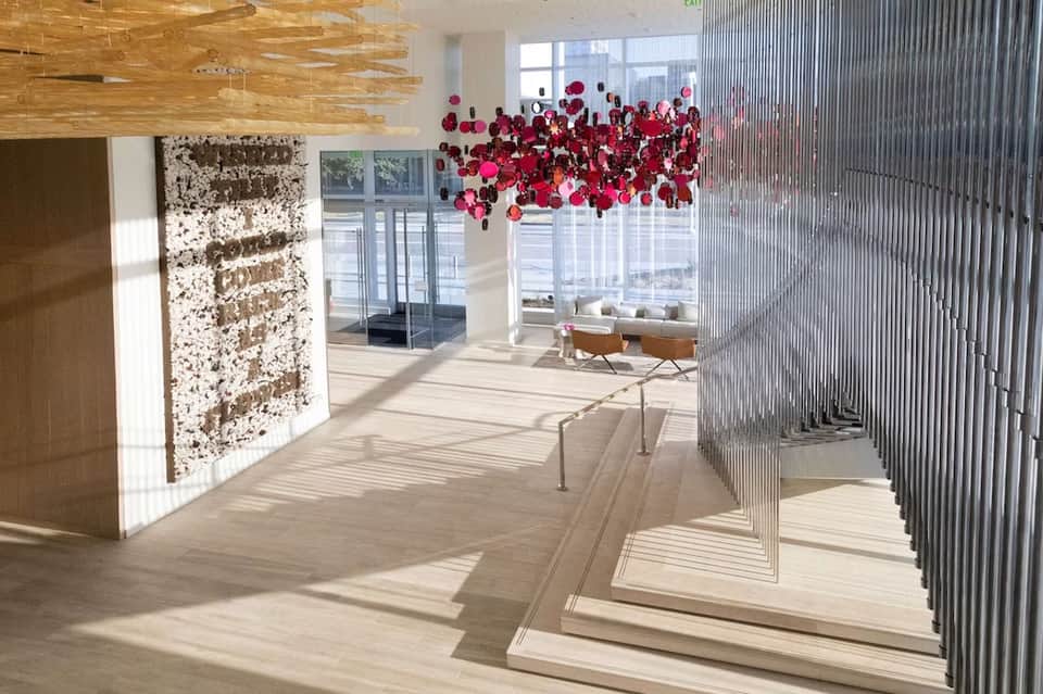 Bright hotel corridor with floral ceiling installation and geometric window treatments