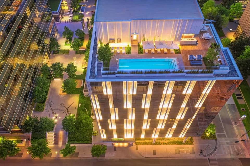 Nighttime aerial view of rooftop pool and illuminated building with modern architecture