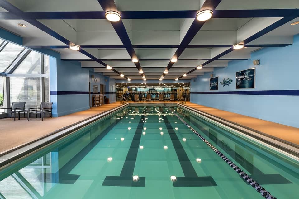 Indoor lap pool with lane dividers, blue water, ceiling lights, and modern athletic facility