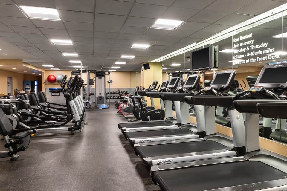 Fitness center with treadmills, exercise bikes, dumbbells, fitness balls, and bright lighting