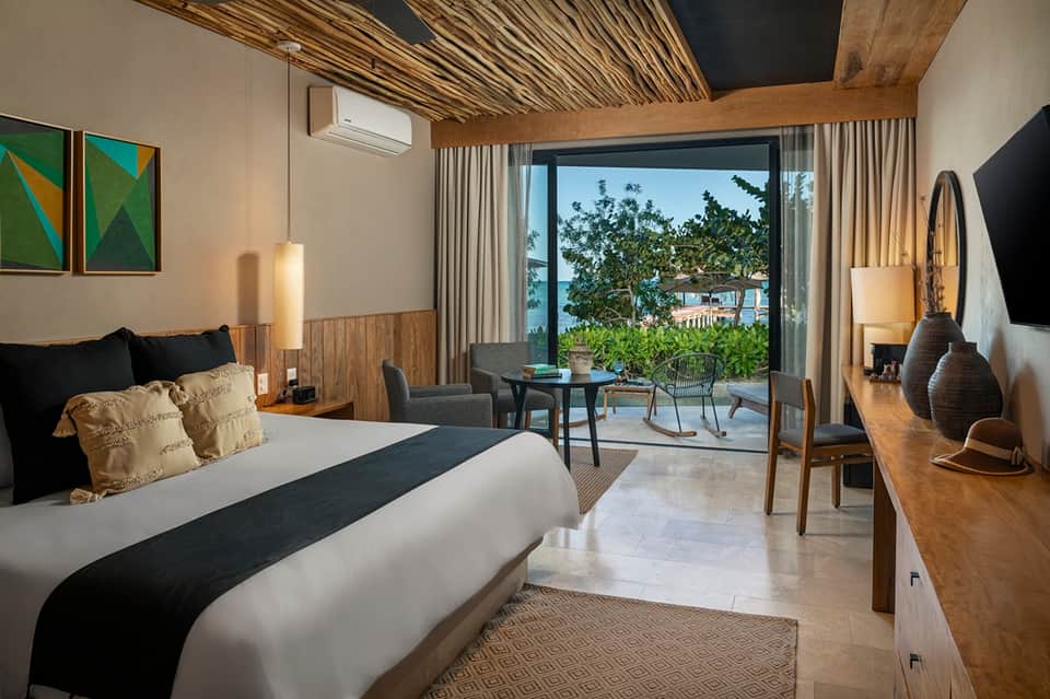 Tropical resort bedroom with ocean view patio, wooden headboard, and modern furnishings