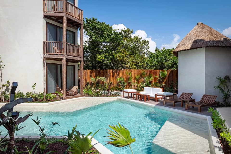 Private resort villa with turquoise pool, wooden deck, and thatched-roof structures