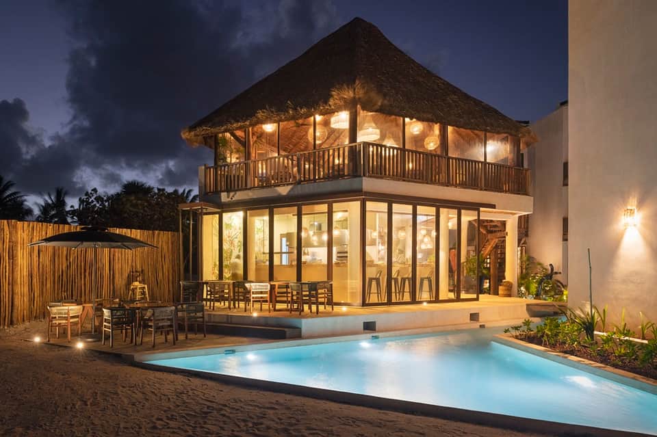 Beachfront villa at dusk with illuminated windows and private pool