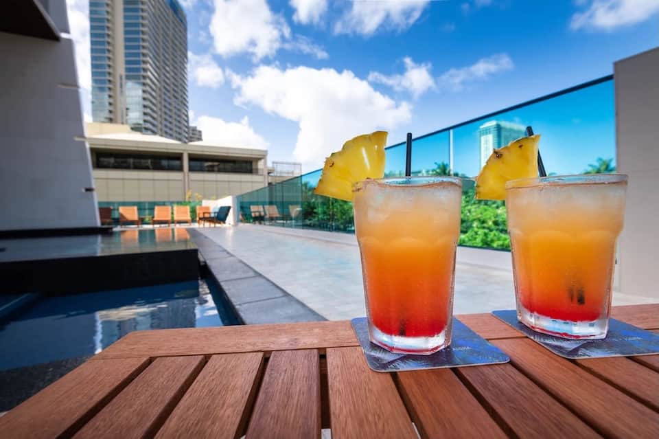 Tropical cocktails with pineapple garnish on rooftop pool deck overlooking city
