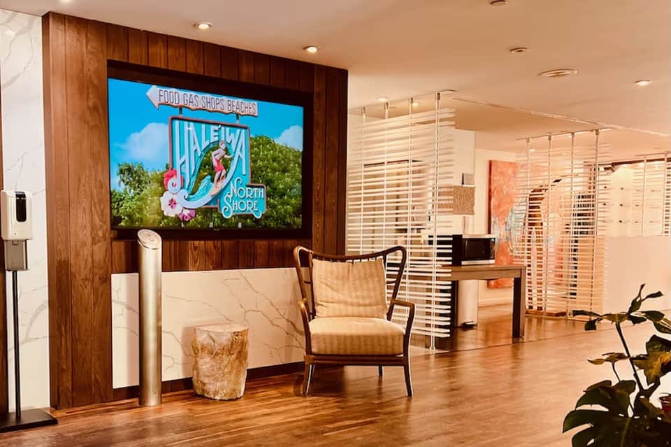 Hotel lobby interior with TV displaying retro sign, modern furniture, and wooden accents