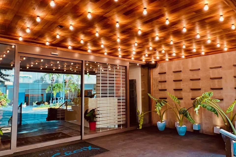 Modern pool entrance with ambient lighting, glass doors, and tropical plant decorations