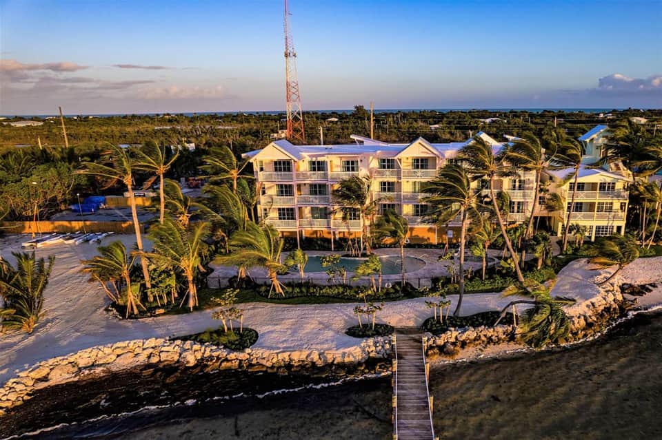 Aerial view of waterfront resort property with pools and palm tree landscaping