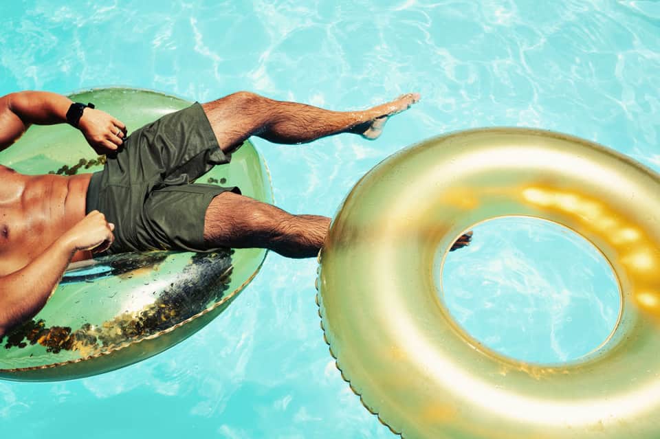 Man relaxing on inflatable pool floats in bright turquoise water