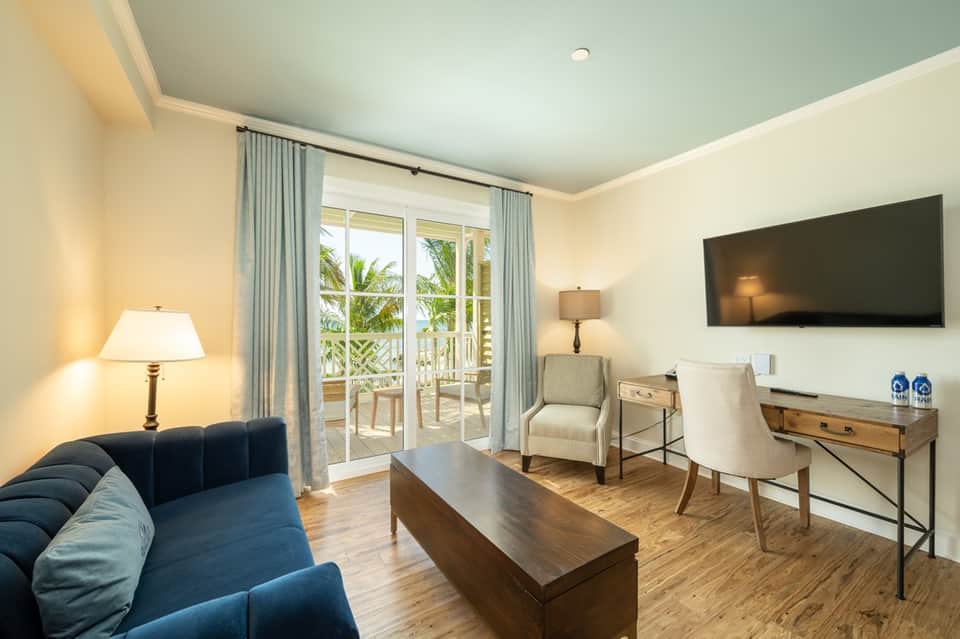 Resort suite living room with blue sofa, balcony doors, and flat-screen TV
