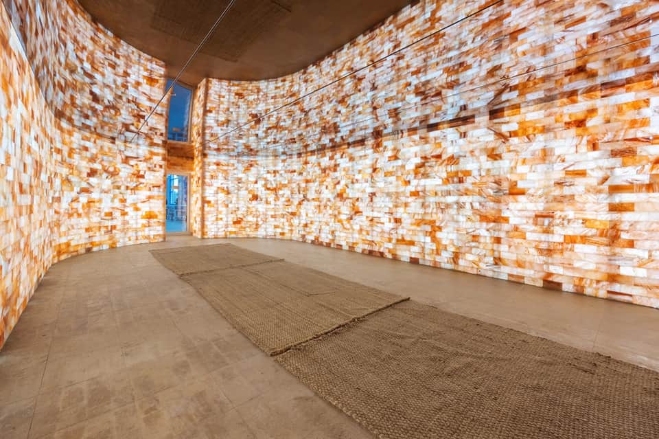 Modern spa sauna interior with orange and white tile walls and wooden benches