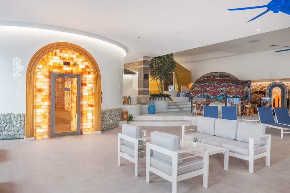 Spa entrance with illuminated arched doorway, white seating, and modern wellness facility interior